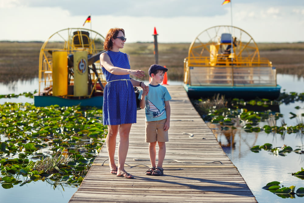 A mother and son walking along a boardwalk about to board their everglade tour boat